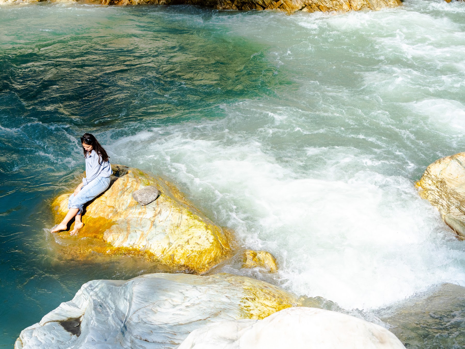 Guest sitting on a rock beside the rushing Parvati River